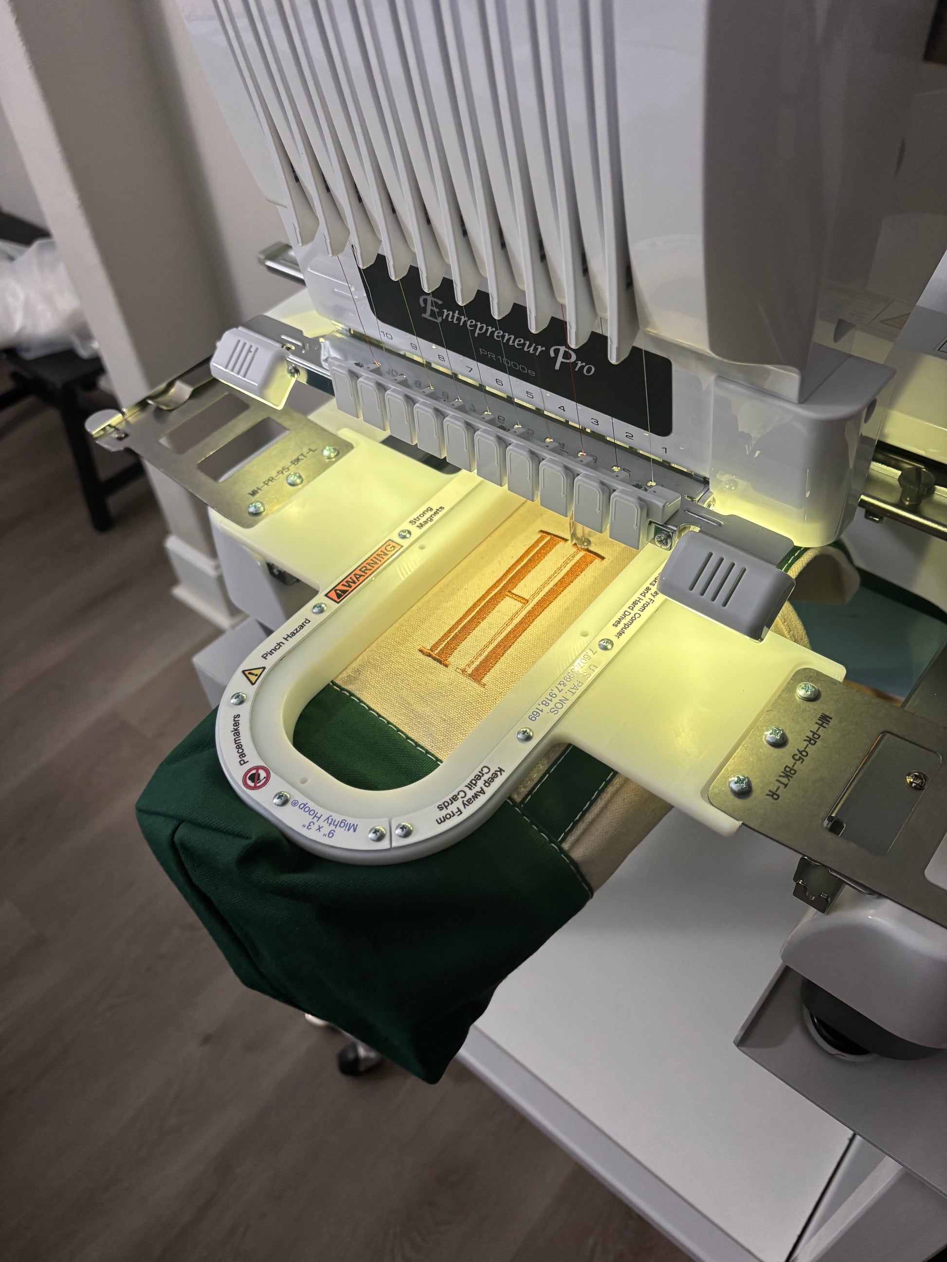 Embroidery machine with a green fabric on a wooden floor