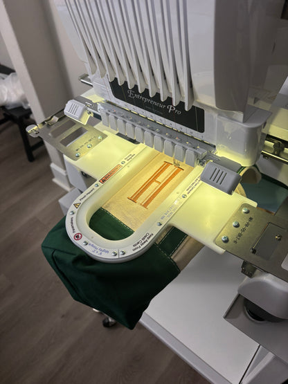 Embroidery machine with a green fabric on a wooden floor