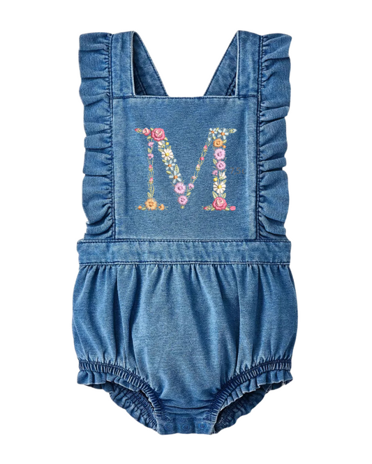 A denim ruffle romper for babies with a custom embroidered floral initial on the front.