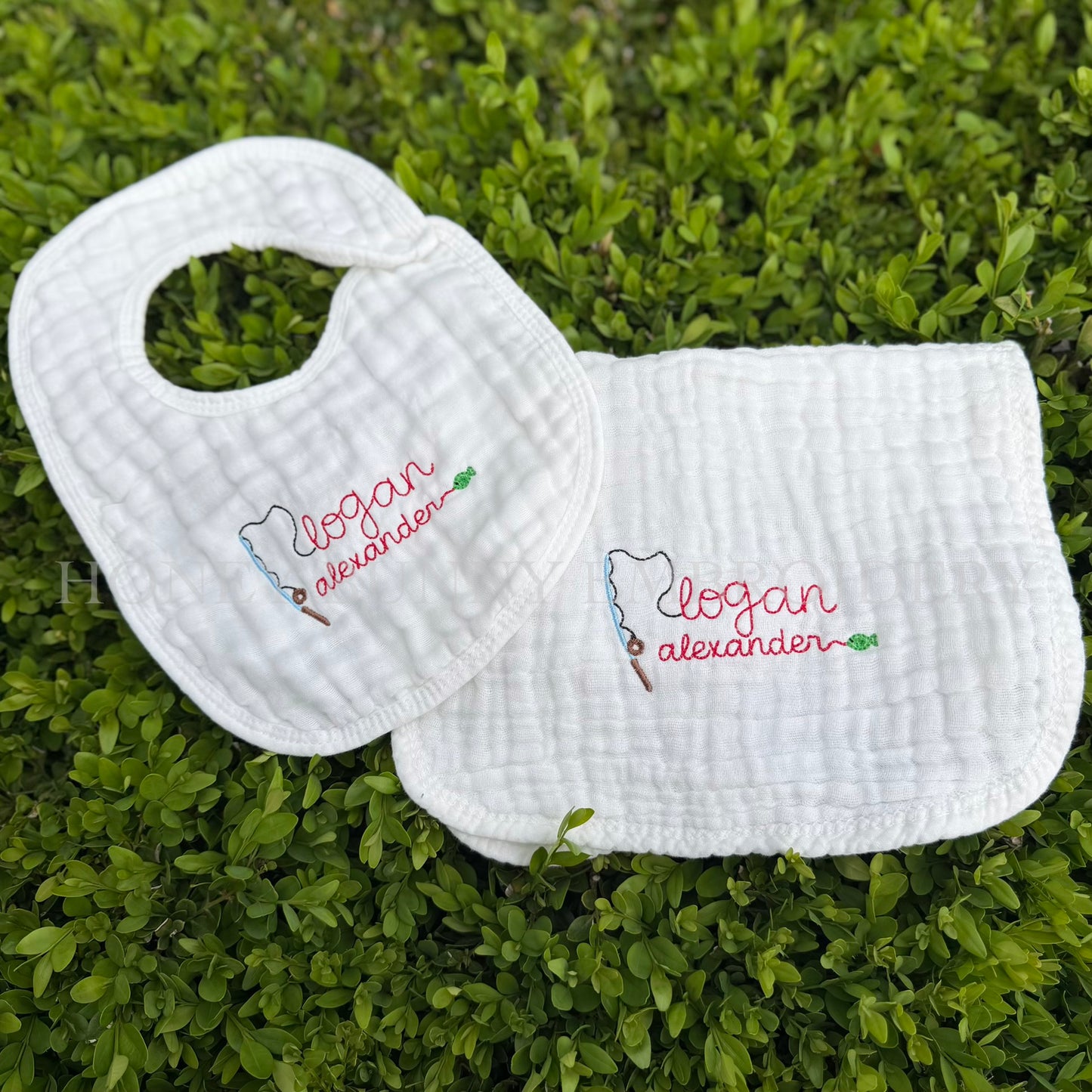 Two white bibs with embroidered names on a grass background