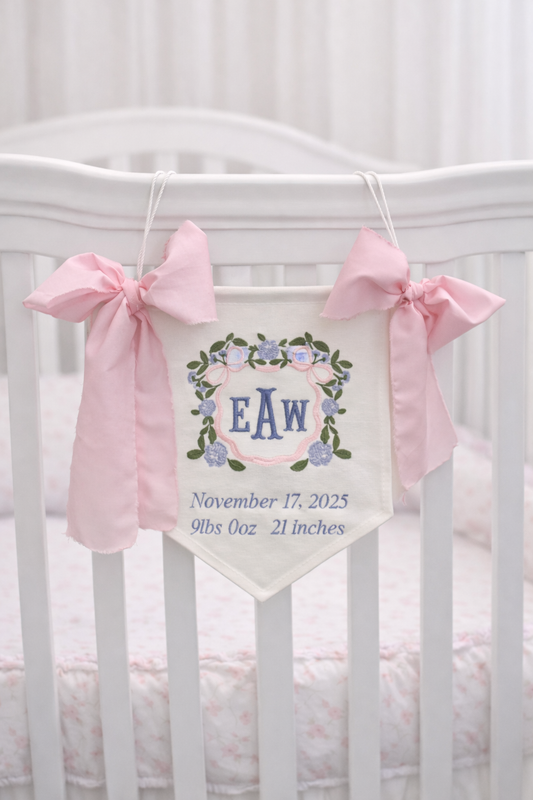 Baby nursery banner with pink bows hanging above a crib
