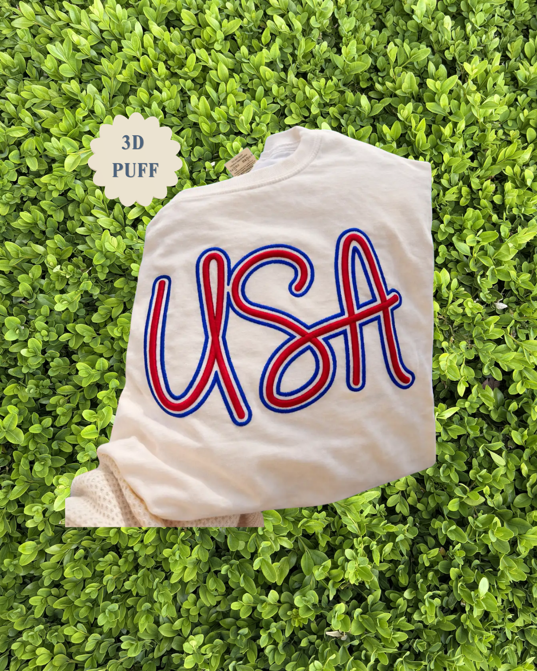 White sweatshirt with 'USA' in red and blue on a green grass background