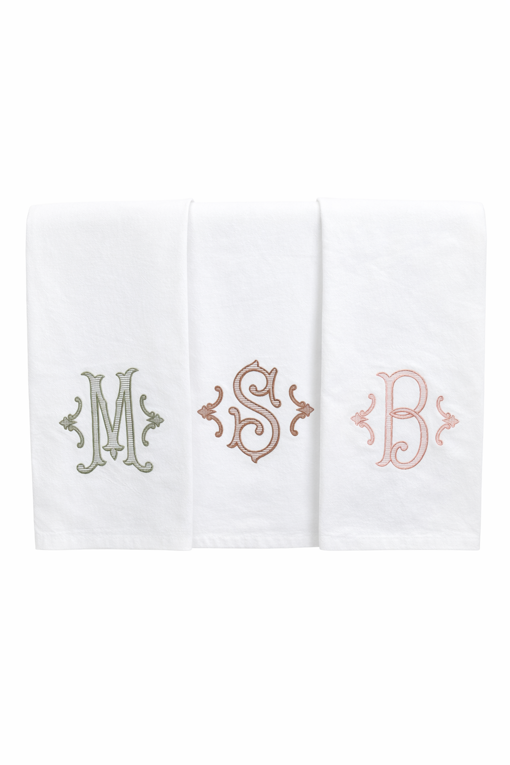 Three white towels with embroidered initials 'M', 'S', and 'B' on a white background