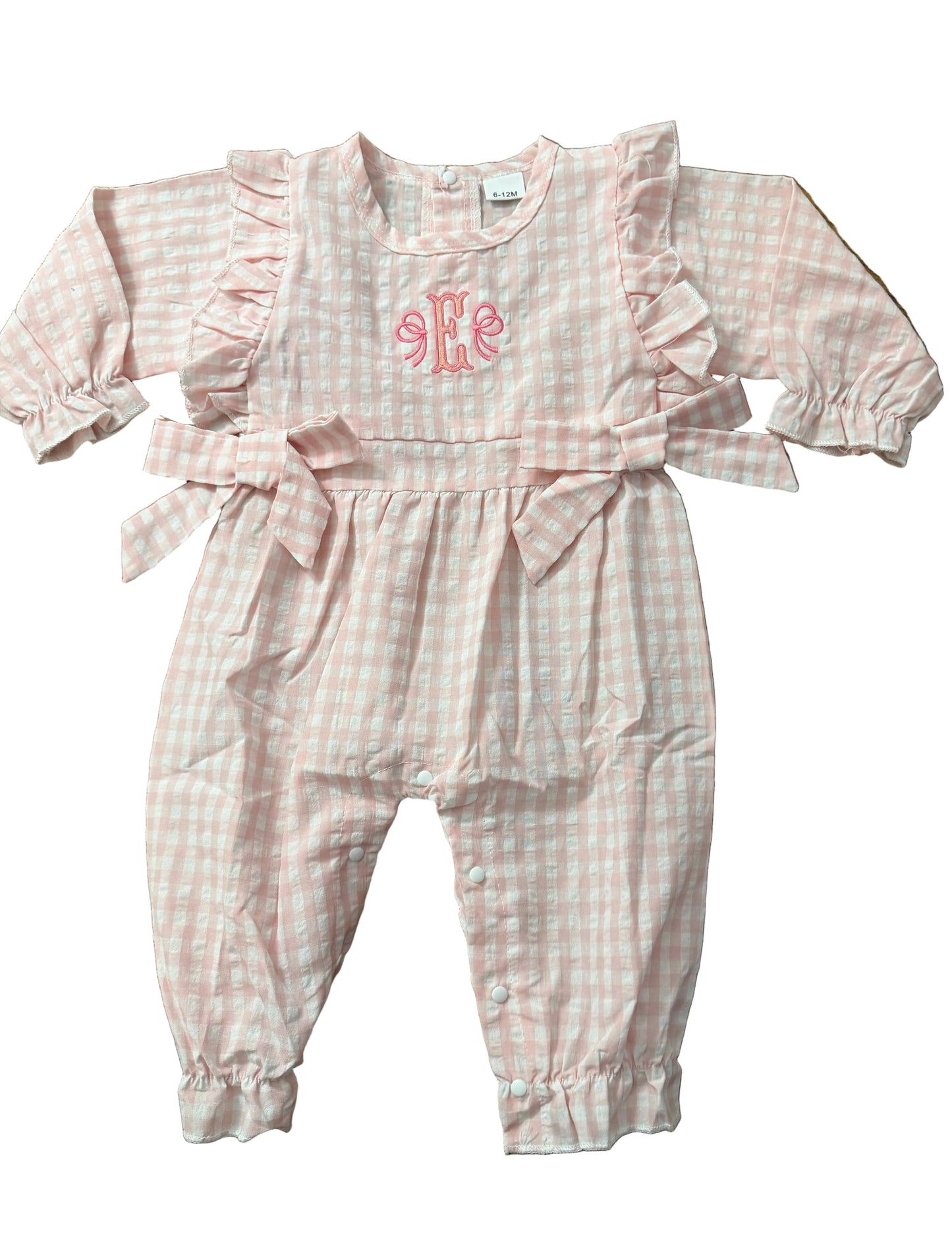 Pink checkered baby outfit with a heart design on a wooden surface