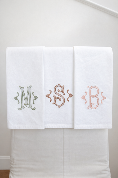 Three white towels with embroidered initials on a white background