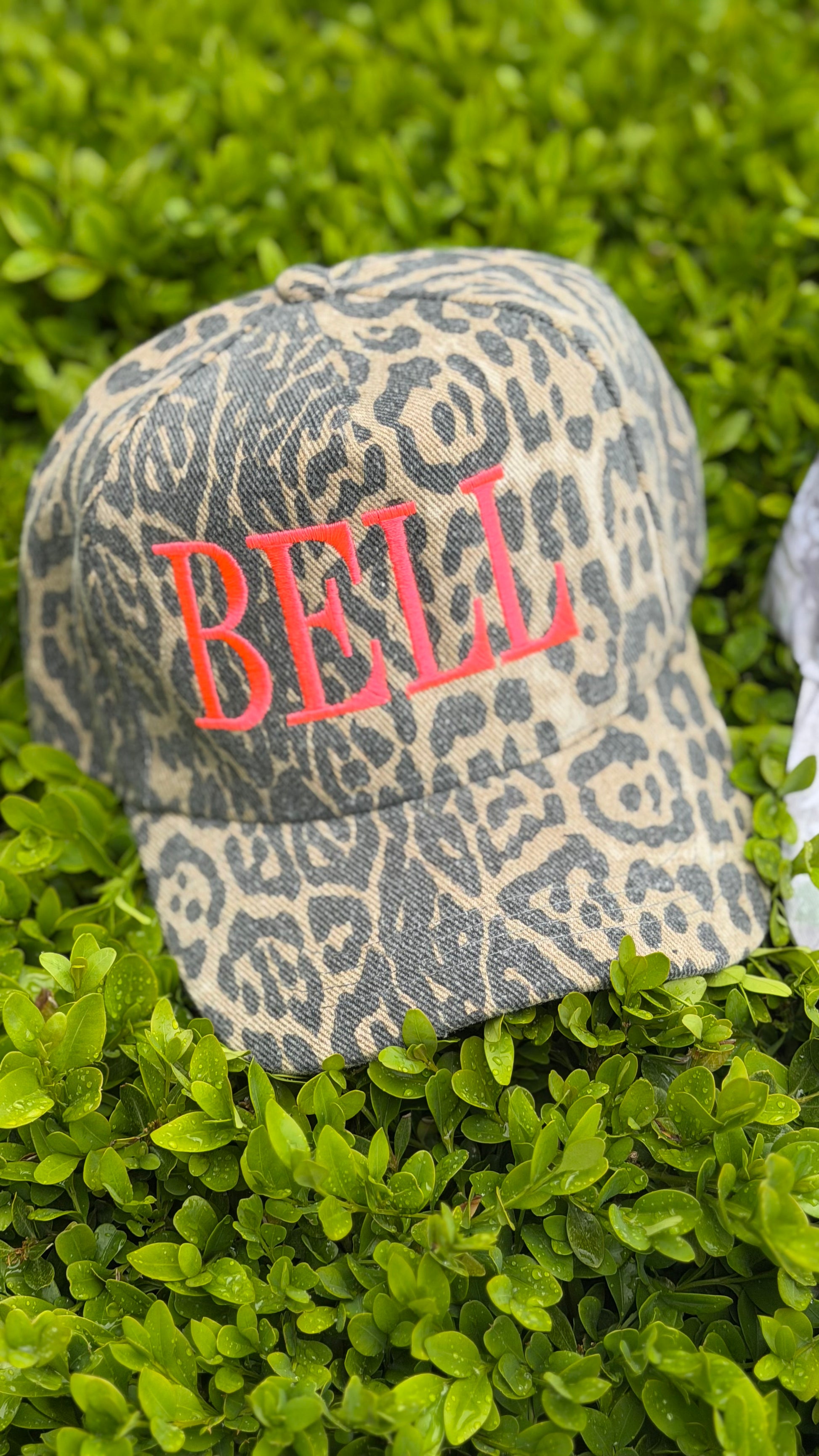 Leopard print cap with 'BELL' embroidered on it, placed on green grass.