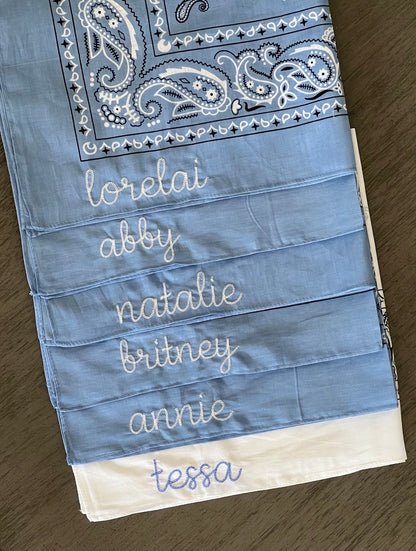 Blue bandana with embroidered names on a wooden surface