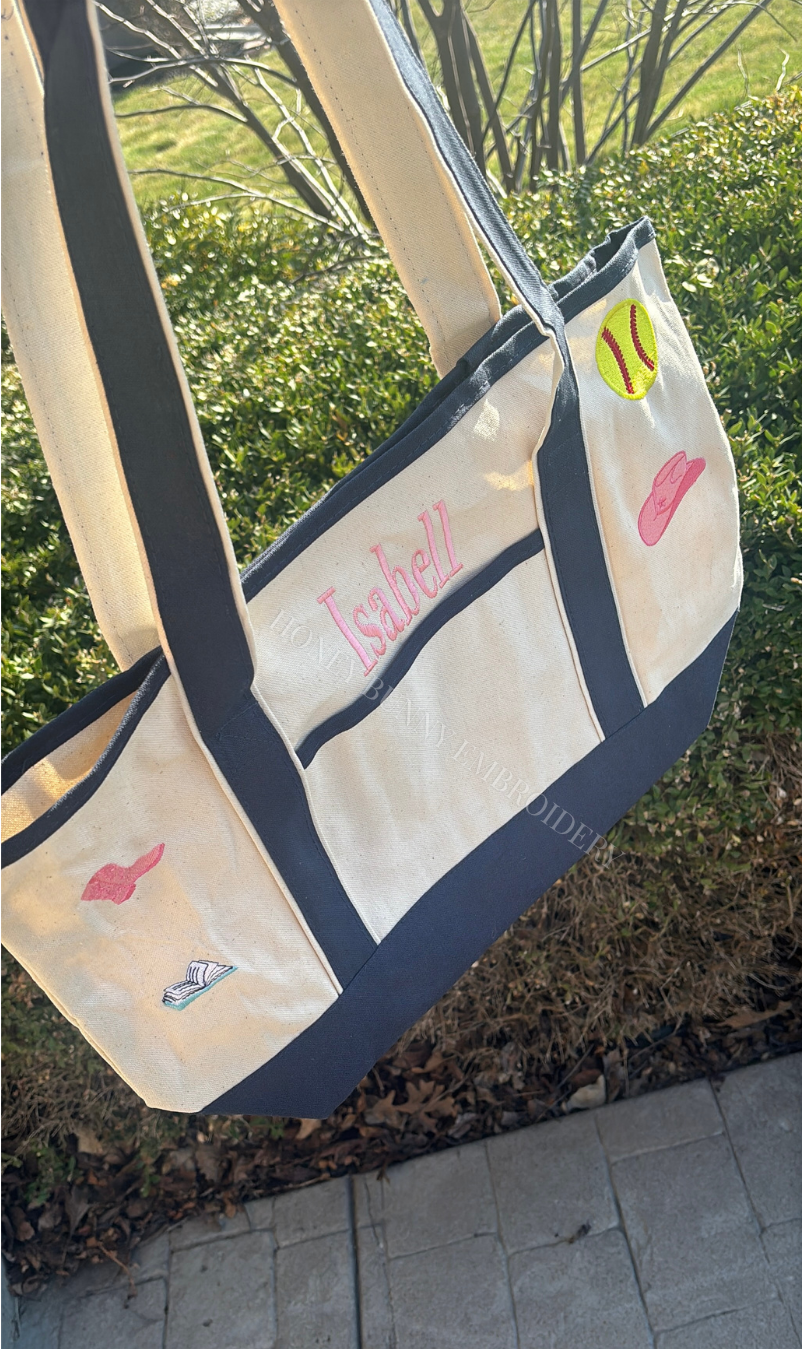 White tote bag with pink text and graphics on a grassy background
