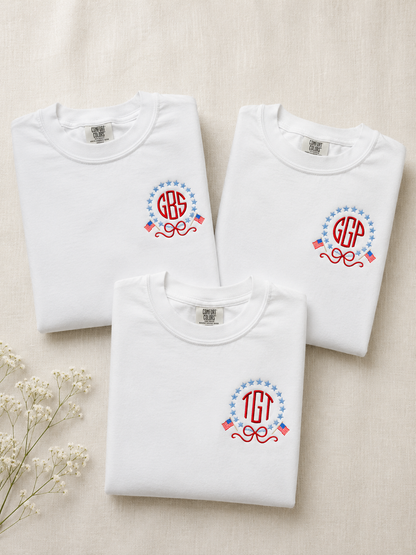 Three folded white sweatshirts with monogram designs on a beige background