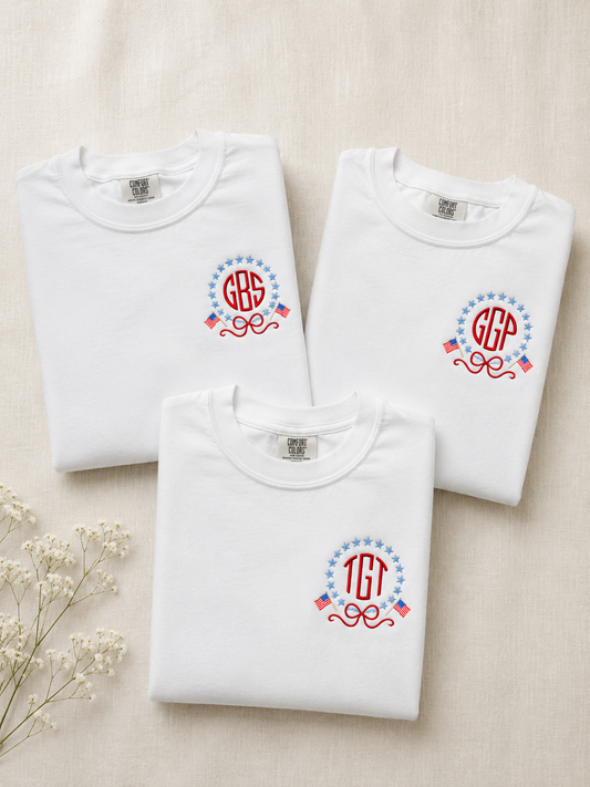 Three folded white sweatshirts with monogram designs on a beige background