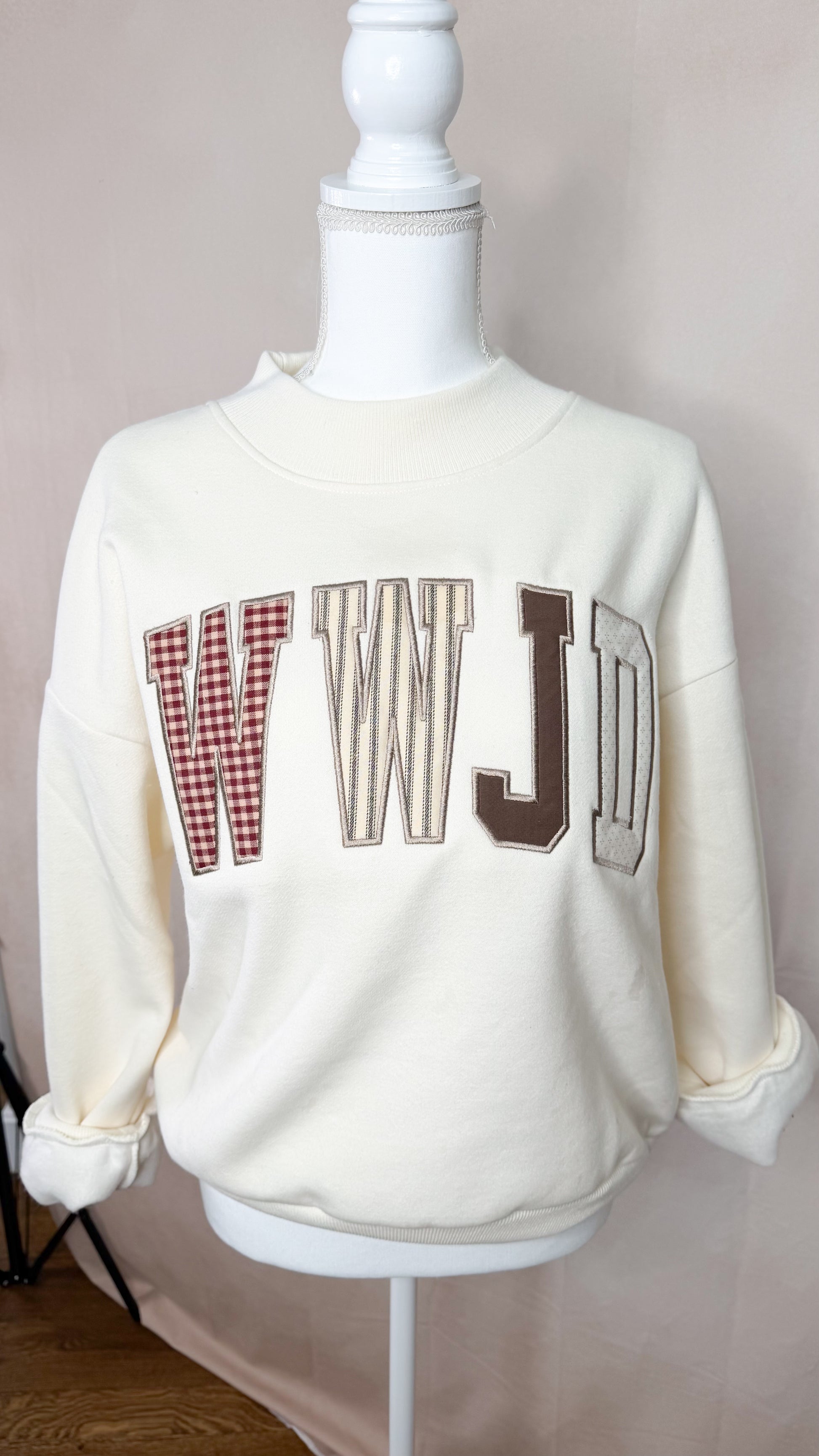 White sweatshirt with text and checkered design on a mannequin against a neutral background