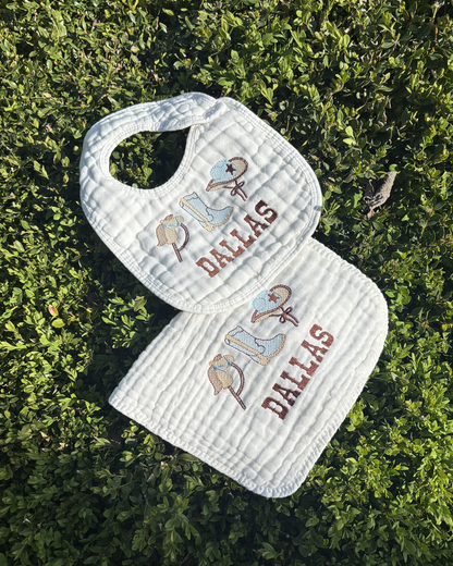 White bib and burp cloth set with 'Dallas' and bull design on grass